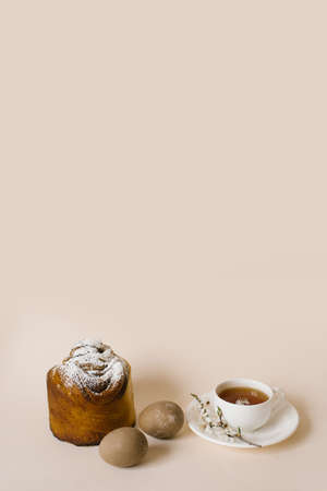 A traditional Easter cake sprinkled with powdered sugar, colored beige eggs and a cup of black tea...