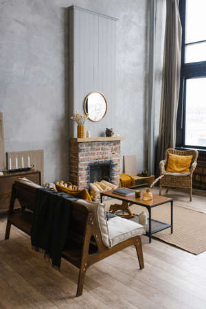 Scandinavian-style interior with fireplace, rattan chair in the trendy colors of 2021 gray and yellowの写真素材