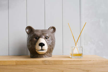 Ceramic souvenir bear head and home fragrance-diffuser on a wooden shelf. Home Decorの写真素材