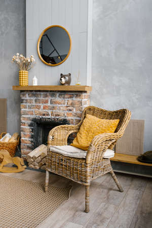 A Scandinavian living room in the gray and gold colors of 2021. The interior of a country house with fireplace and wicker chairの写真素材