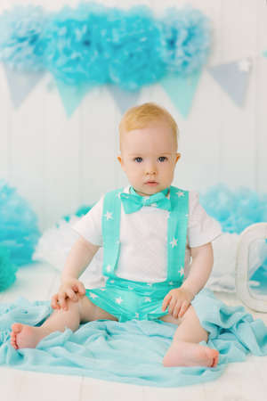 Portrait of a beautiful one-year-old boy in turquoise clothing with stars in the photo zone for his first birthday. Children's entertainment centerの写真素材
