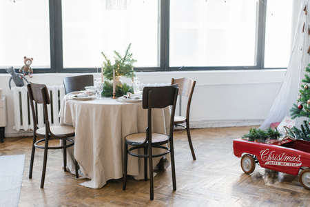 Round table with wooden chairs, decorated for a Christmas family dinner. Living room interior
