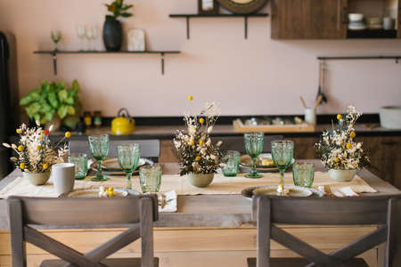A beautiful festive dining table in the rustic style. Dried flowers in a ceramic vase on the tableの写真素材