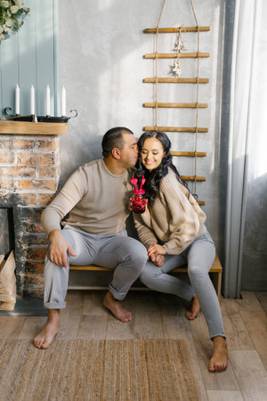 A couple in love are happy together, they keep a mug with hearts with juice and two tubes in the living room. The concept of celebrating Valentine's Dayの写真素材