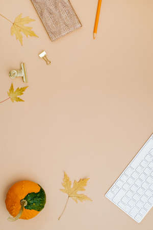 Autumn flat lay, top view of home office desk. workspace with keyboard, pumpkin, leaves, notebook and pen on beige background, flat lay, top viewの写真素材