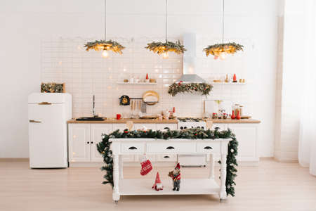 Interior of a bright kitchen with a table in a Scandinavian style island, decorated for Christmas and New Yearの写真素材