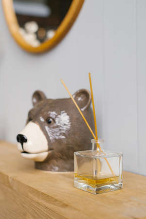 Ceramic souvenir bear head and home fragrance-diffuser on a wooden shelf. Home Decorの写真素材