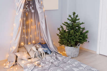 Stylish modern children's room. Children's bed with awning. Christmas tree in a wicker basket. Scandinavian style interiorの写真素材