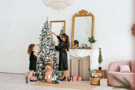Mom and daughters decorate the Christmas tree for the New Year celebrationの写真素材