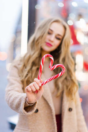 A heart made of two candy canes in the hands of a girl. The concept of the Valentine's Day holidayの写真素材