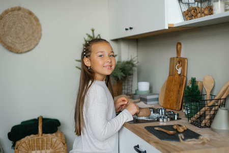 Six-year-old girl cooks ginger Christmas cookies in the kitchenの写真素材
