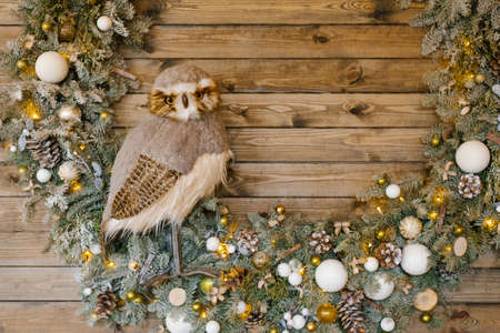 Christmas artificial wreath with white and gold ornaments and a toy owlの写真素材