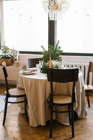 A dining table with wooden chairs, decorated and served for Christmas dinner against the background...