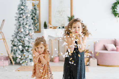 Two happy kids celebrating new year and Christmas eve at home. They turn into confetti, which flies...