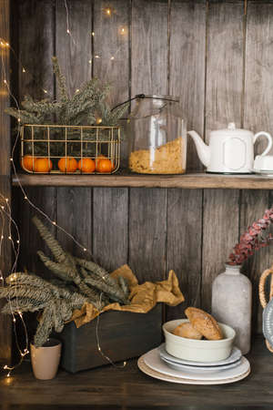 A basket with tangerines and fir branches is on a shelf with kitchen utensils. Christmas home decorの写真素材