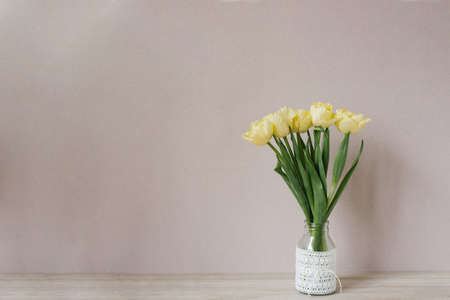 Bouquet of yellow tulips in a vase. Spring flowers. Bouquet in a vase. Cozy still life. Copy space. A festive greeting.の写真素材