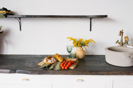 Bright, modern kitchen with stone sink. Loaves of fresh homemade bread and a sprig of tomato on a...