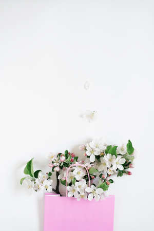 Sell concept. Pink shopping bag on white background decorated with spring apple tree flowersの写真素材