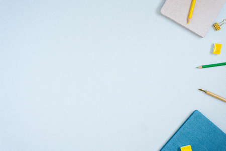 A frame of notepads, colored pencils, watercolors and a pen on a blue background. Copy space for a blogger, artist, or calligrapherの写真素材