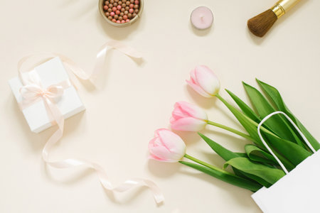 Flat lay composition with cosmetic products for makeup and pink tulips on a beige backgroundの写真素材
