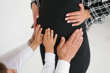 The hands of the son and husband on the stomach of the pregnant mother and wifeの写真素材