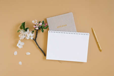 Open notebook with a blank white sheet of paper for copy space, notepad, pen and white flowers on a...