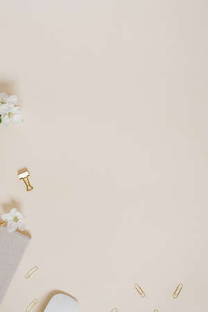 Female workspace of a table with delicate flowers of an apple tree, a notebook, a pen, paper clips...