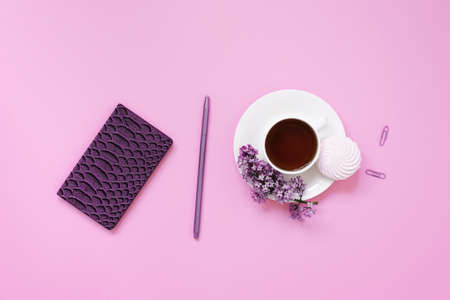 A cup of tea, notebooks, a pen, a bouquet of lilacs on a purple background. purple spring flowers....