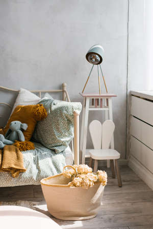 Stylish children's room of the child. Wicker basket with flowers, pillows on the bed mint and brownの写真素材