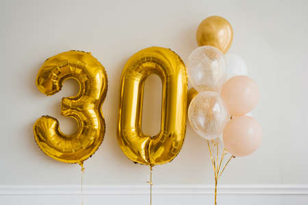 Decor for the celebration of the 30th anniversary. Balloons of gold and white color