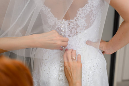 The bridesmaids help the bride put on her wedding dress. close-up of handsの写真素材