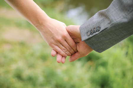 A man holds a woman's hand. Hands of the bride and groom with an engagement ring close-up