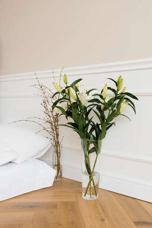 White lily flowers in a vase, tree branches in a vase. Details of the interior decor of the houseの写真素材