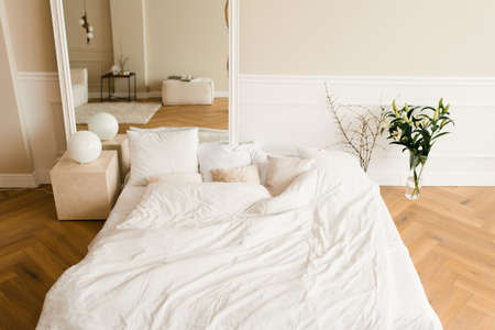 A cozy bed on the floor, a large mirror in a classic modern bedroom. Interior of the houseの写真素材