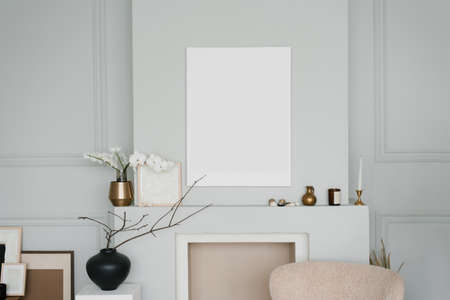 Stylish minimalist Scandinavian living room decor in grey. Mockup of a painting over the fireplace,...