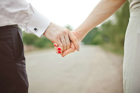 A man holds a woman's hand. Hands of the bride and groom with a wedding ring close-upの写真素材