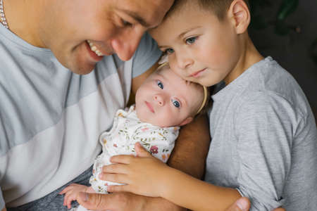 Father and five-year-old son hugs newborn daughter and sister