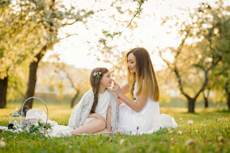 Happy family mom and daughter relax in the fresh air in the park on a blanketの写真素材