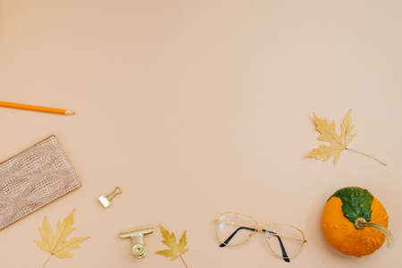 hello autumn concept. Workplace with fallen leaves, pumpkin, notepad, pencils, student glasses, schoolgirl or bloggerの写真素材