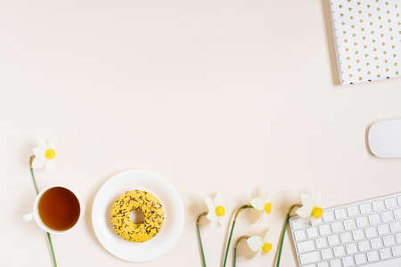 Flat lay lady blogger or freelancer workspace with a keyboard, flowers, office supplies on a beige background. copy spaceの写真素材