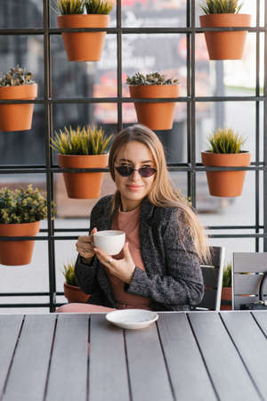 A beautiful pretty girl in a cafe drinking coffee on a summer terraceの写真素材