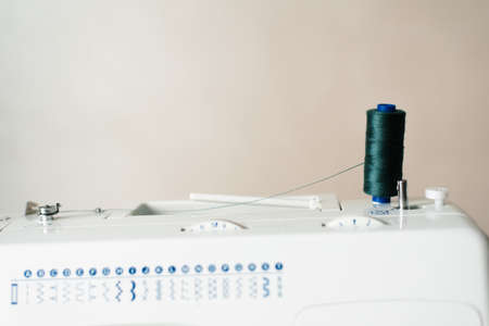 Holder on a sewing machine with threads of emerald color. Concept: atelier, sewing business, sewing...
