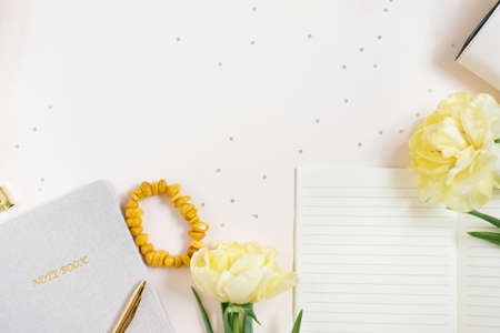 Notepad for daily planning and a pen on a beige background. Yellow tulip flowers and an amber bracelet. The concept of daily planning of life, work, study. copy spaceの写真素材