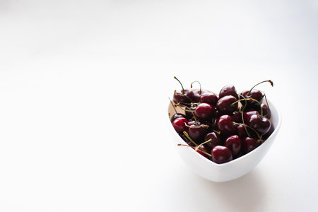 Fresh ripe cherries on a plate in the shape of a heart on a white background with a copy space. Vitamins and healthy nutritionの写真素材