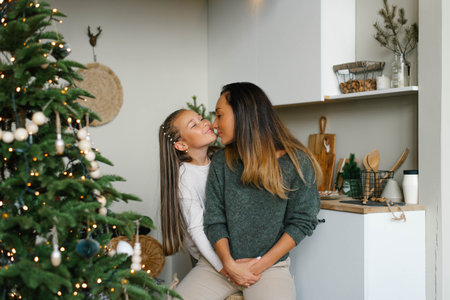 Happy family mom and daughter have fun preparing for Christmas and New Year in the kitchen near the Christmas treeの写真素材