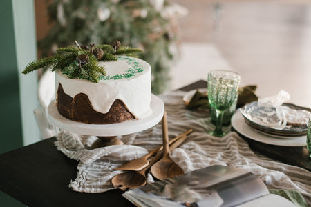 Chocolate cake with white icing, decorated with fir branches for Christmas or New Year on the served dining tableの写真素材