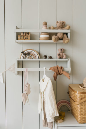 Children's clothes hang on a hanger in the children's room and various toys in a minimalist styleの写真素材