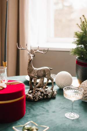 Christmas decor of a festive table with a statuette of a deer and a glassの写真素材
