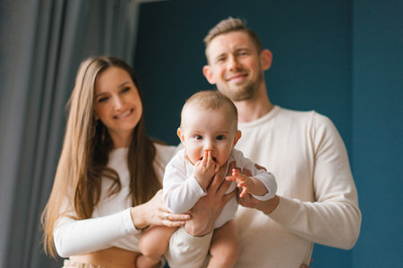 Happy family, mother and father playing with baby at homeの写真素材