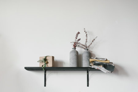 Christmas minimalist decor on a shelf on the wall: eucalyptus in vases, gift box and towelsの写真素材